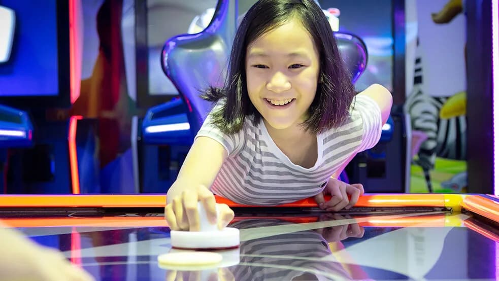Une enfant sourit en jouant à l'air hockey